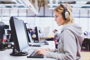adult education, student in headphones working on computer in the library or classroom of university